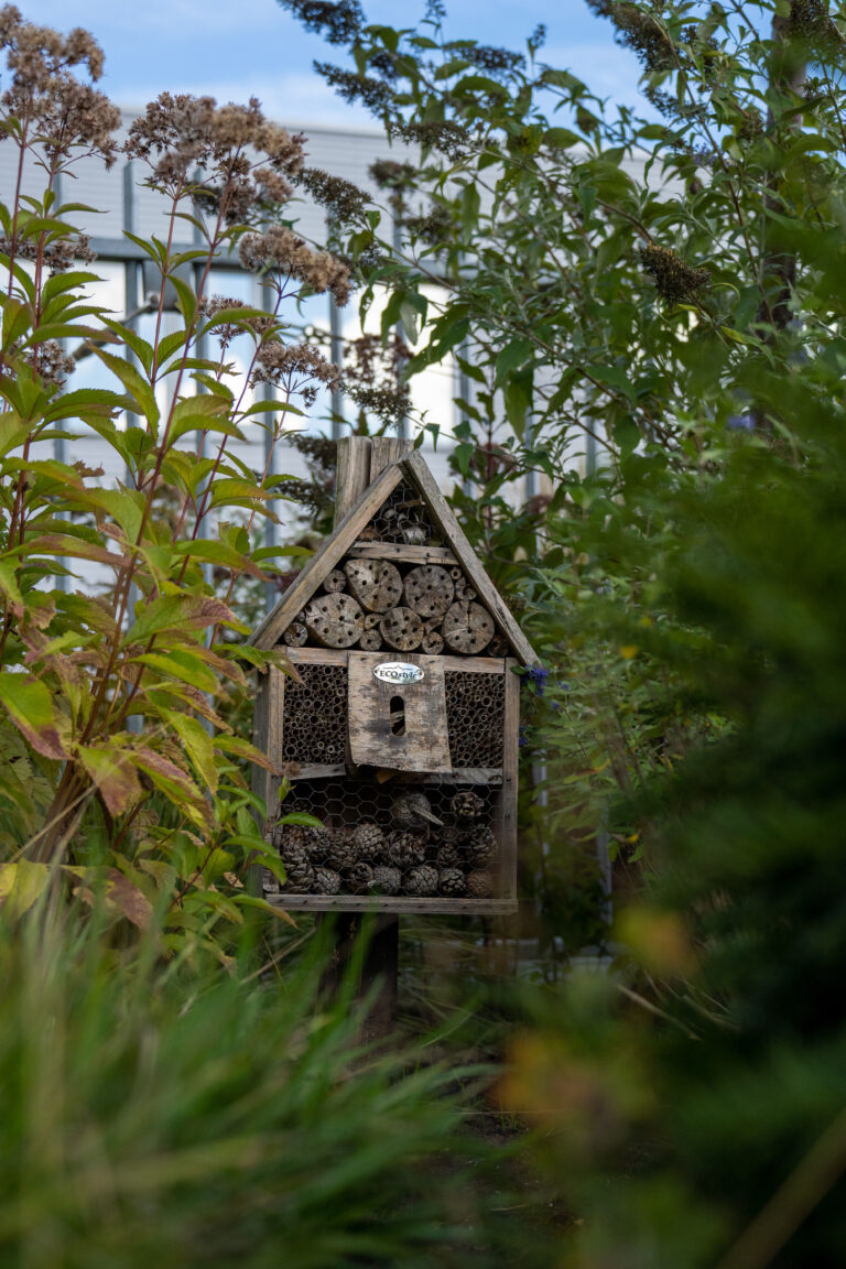 Insectenhotel in een groene tuin, bijdraagt aan biodiversiteit en duurzame werklandschappen.