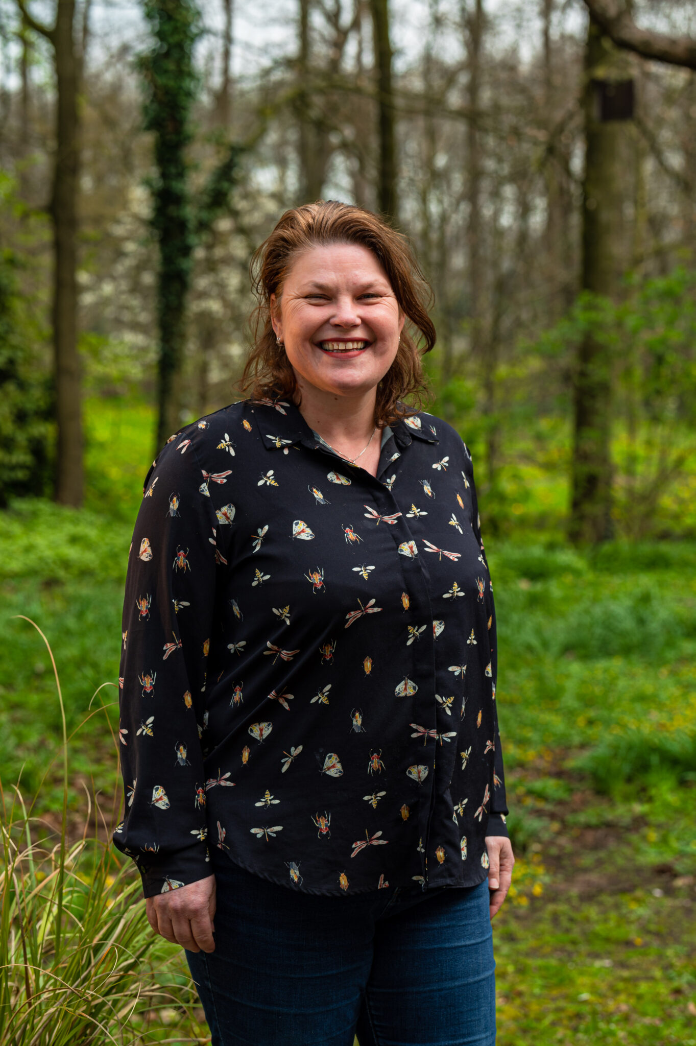 Lachende vrouw in bosrijke omgeving met groene bomen en struiken, natuur landschap.