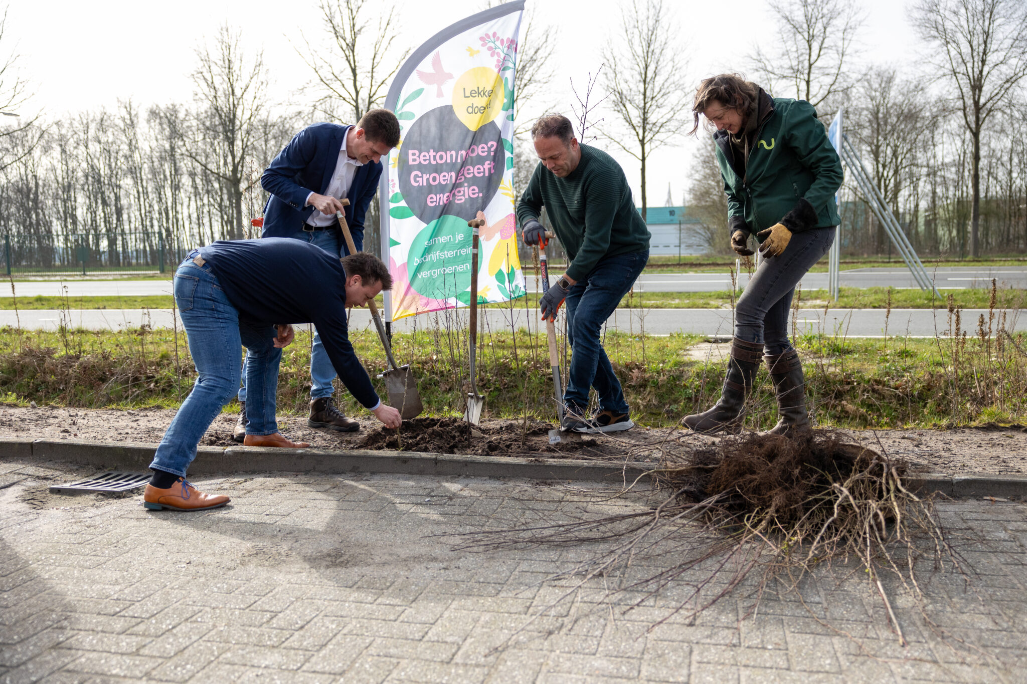 Vier mensen die planten bij een vlag van Groen Geeft Energie