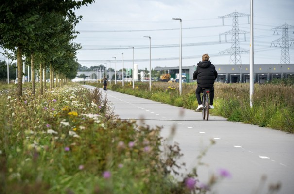 mensen die fietsen langs een bedrijventerrein met groen strook