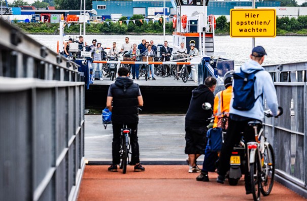 fietsers wachten op de kade tot de volle pont is aangemeerd